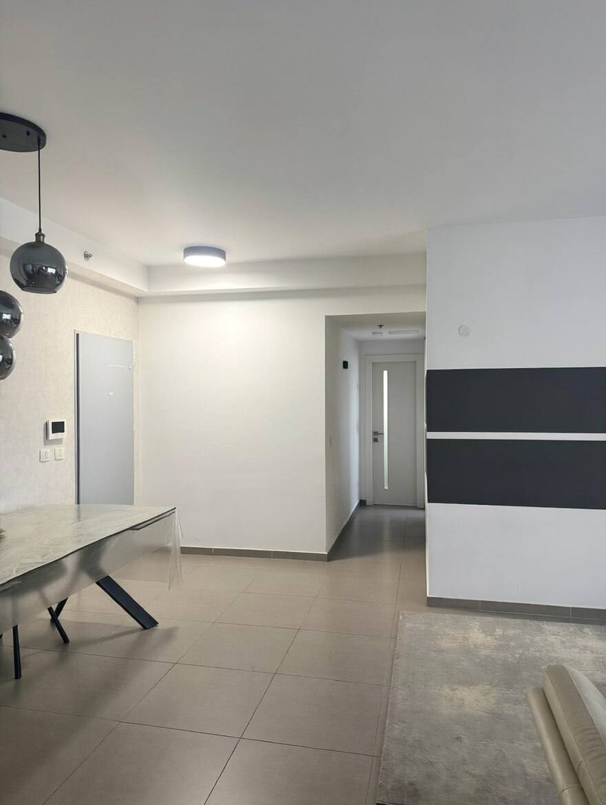 מבט מהסלון אל המסדרון לחדרי השינה, ריצוף בהיר וקירות לבנים